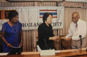 Handover ceremony beneath a Sri Lanka-Thailand Society banner