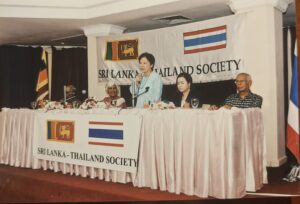 Speakers at the head table during a Society gathering, flanked by both national flags