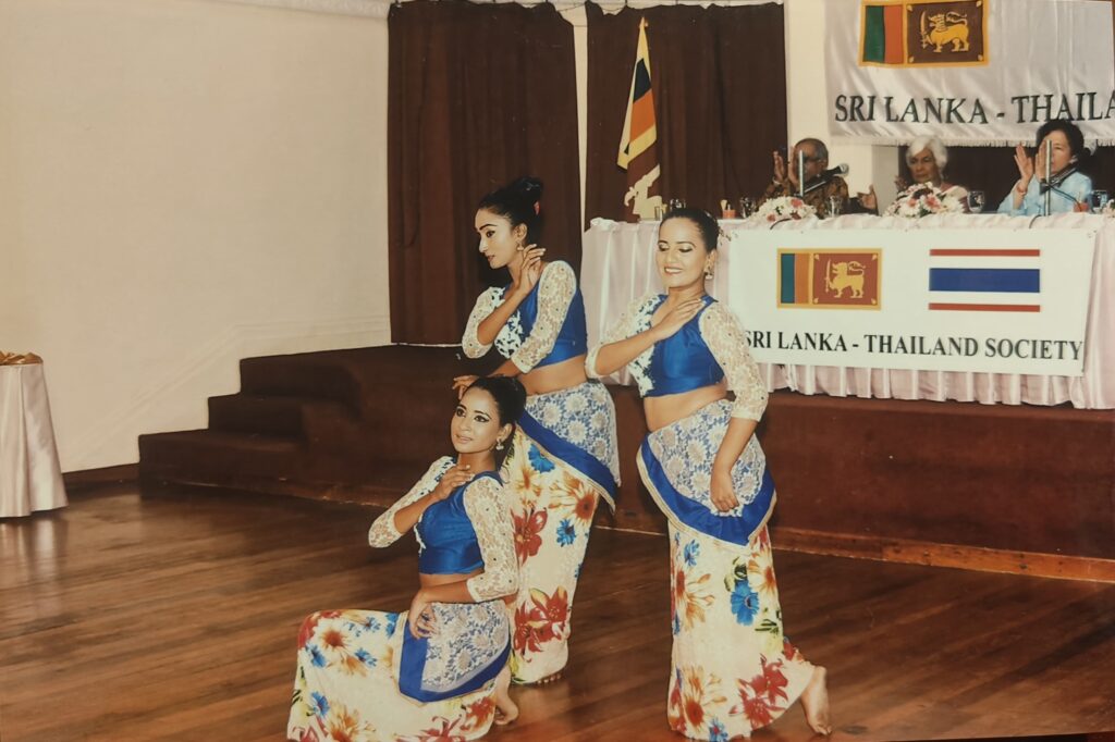 Sri Lankan dancers performing in front of the Sri Lanka-Thailand Society banner